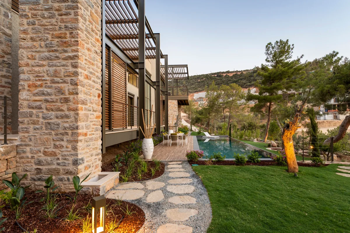 A contemporary stone-faced house surrounded by mature planting